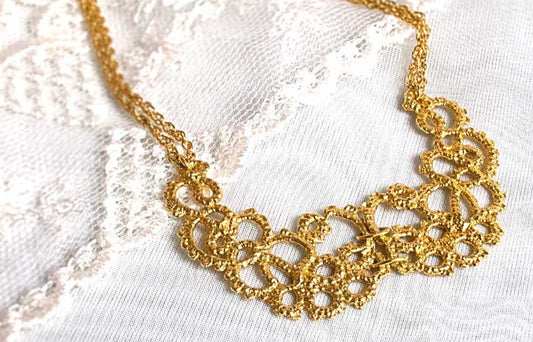 a gold necklace cast from a lace design, laid on delicate white lace