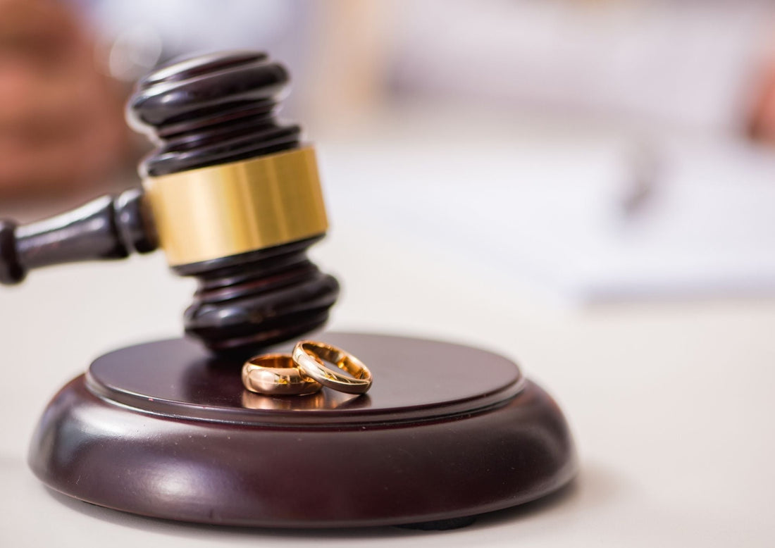 A wooden judge's gavel. On the block are two gold wedding rings.