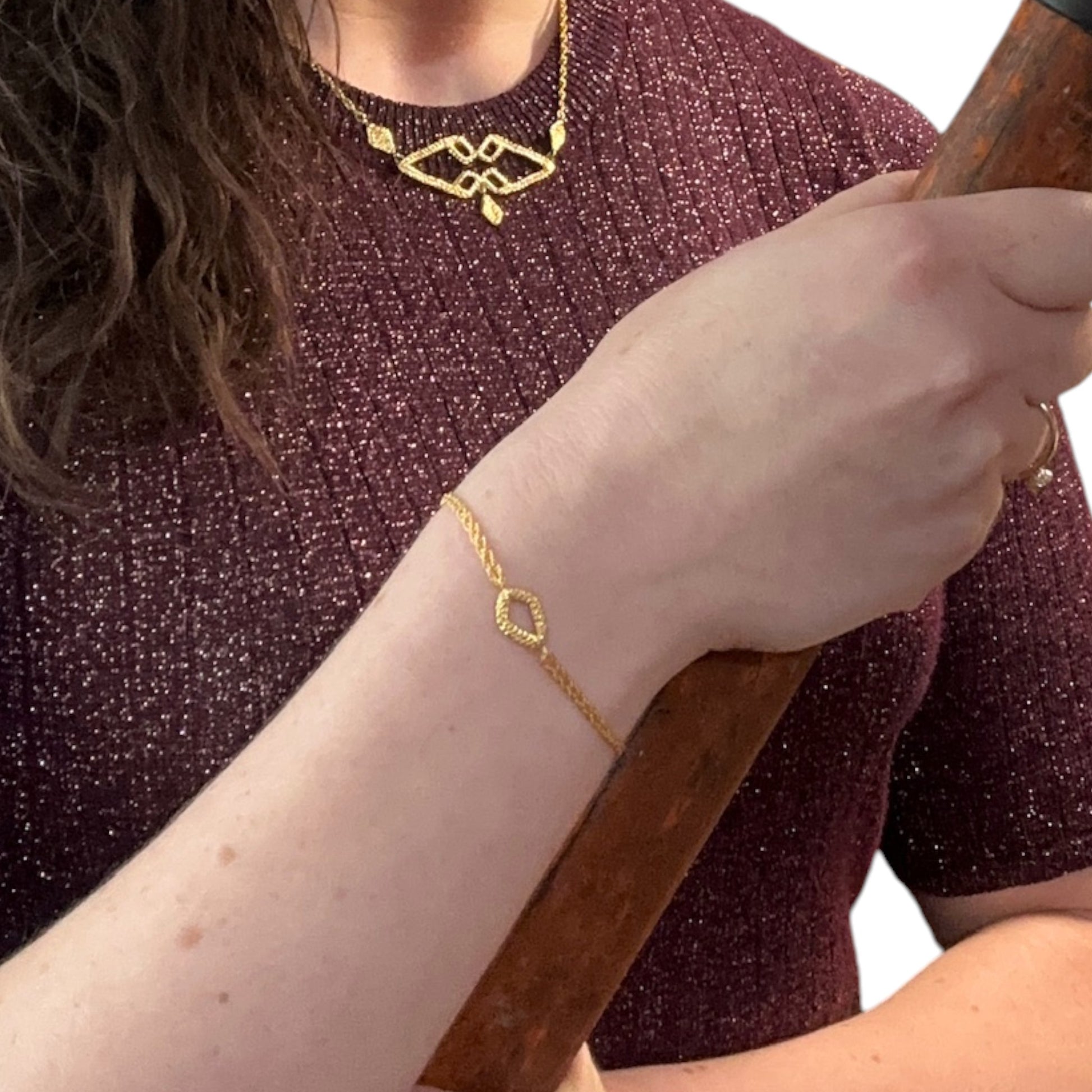 delicate geometric gold bracelet being worn as well as a geometric gold necklace