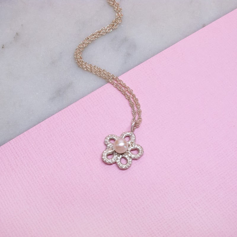 Silver lace and pearl forget me not flower necklace on pink surface